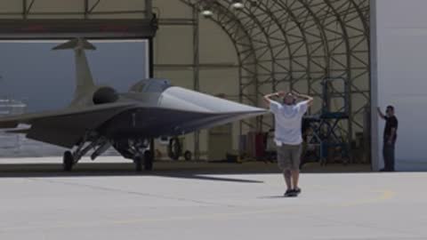 Ground crew member signals in front of the X-59 aircraft.