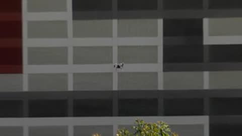 Drone flying close to building facade with windows.