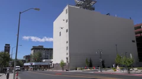 Drone flying near large white building in city.