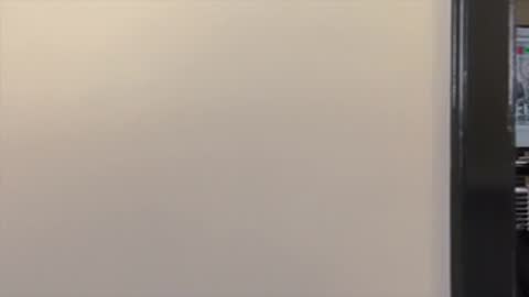 Pan across a blank wall revealing a monitoring screen.