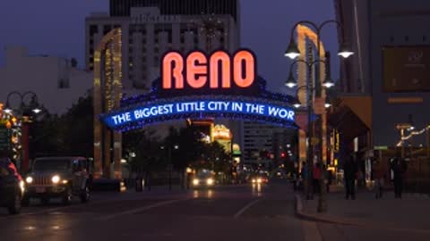 Night view of Reno arch with illuminated lights and street traffic.