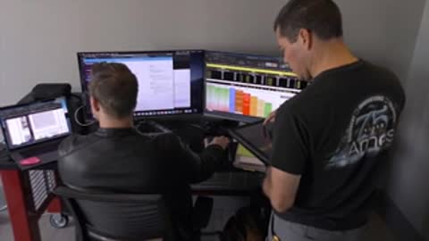 Two men working at desks with computers and monitors.