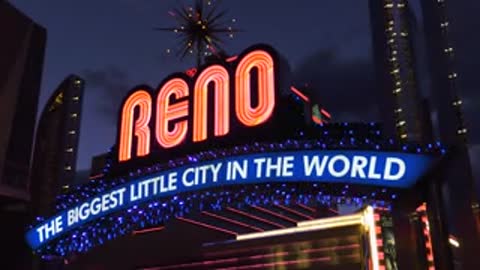 Close-up of illuminated Reno arch sign against night sky.