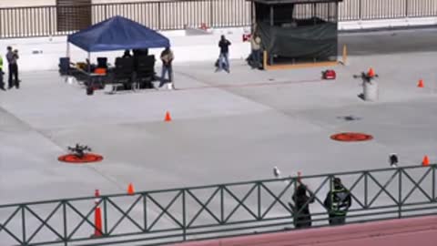 Ground view of drone staging area with cones and people watching.