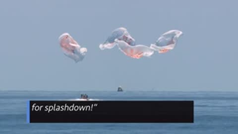 Spacecraft splashing down in the ocean with parachutes detaching.