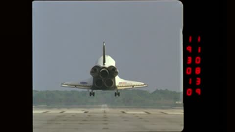 Space Shuttle Orbiter landing on a runway, filmed from a distance with a red data panel on the right.
