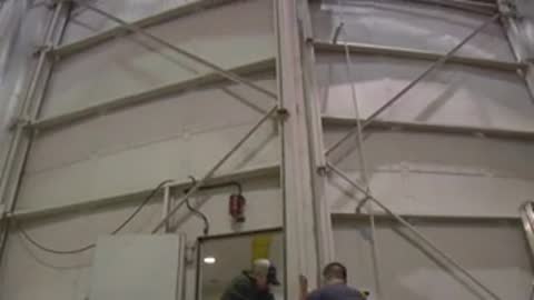 Large mechanical testing arm and heavy metal doors inside a facility
