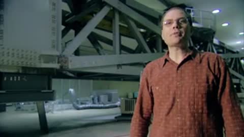 Man gesturing toward machinery in an industrial testing facility