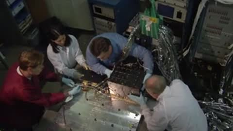Test cell sign and engineers assembling hardware components on a table