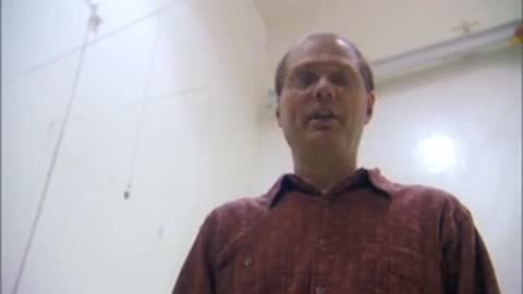 Man speaking while looking upward inside a plain white room