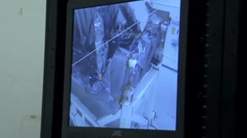 Monitor showing live footage of a mechanical structure inside a test chamber