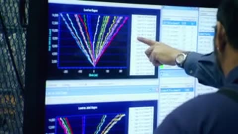 Close-up of a person pointing at data charts displayed on a monitor