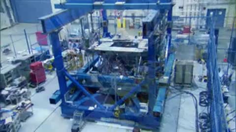 Technicians operating hydraulic pumps while industrial structure is visible nearby