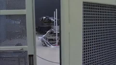 Person opening a mesh enclosure door in a laboratory setting
