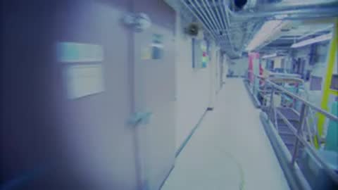 Fast tracking shot moving down a long white hallway inside the facility