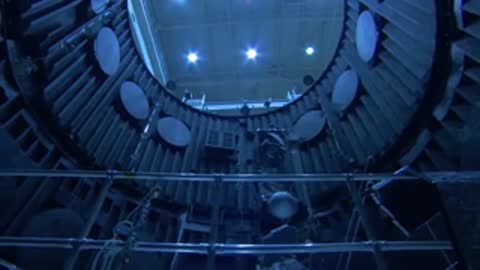 Inside view of a large vacuum chamber with technician working nearby