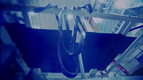 Black equipment harnesses hanging from overhead metal structures in a cleanroom