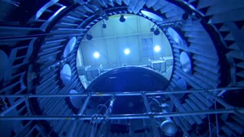 A wide shot looking out of a large circular hatch inside the vacuum chamber.