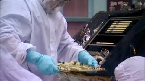 A close-up of gloved hands soldering wiring and circuit boards during equipment assembly.