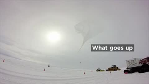 Helium-filled balloon launching over Antarctica in snowy terrain.