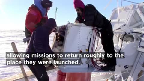 Scientists working on recovered balloon instrument module in snow.