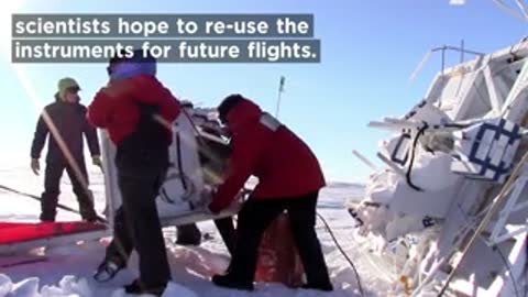 Scientists preparing equipment near red airplane on snow in Antarctica.