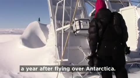 Scientists inspecting recovered NASA-funded balloon experiment in snow.