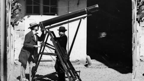 Historical black and white photograph of two men observing with a telescope