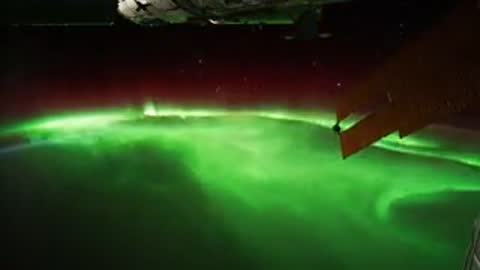 Green aurora borealis glowing over Earth's atmosphere from space station