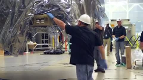 Team of engineers working together to maneuver the suspended wrapped cargo structure