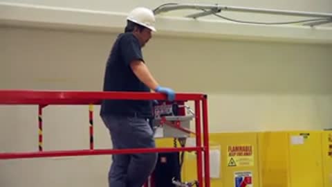 Worker observing the operations from a red elevated platform inside the facility