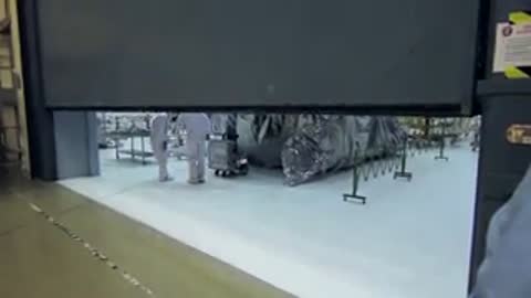 Large mechanical facility door closing slowly over the bright white floor area