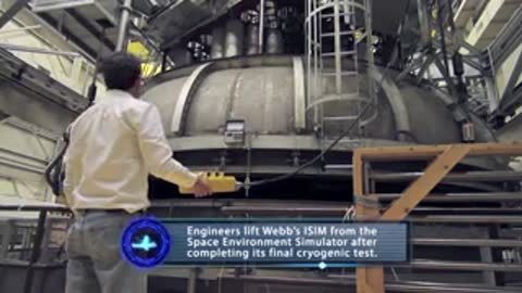 Engineer standing beside a large space simulation chamber in a cleanroom facility
