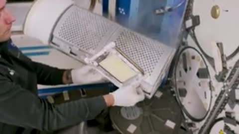 An astronaut handling a cylindrical metal mesh filter