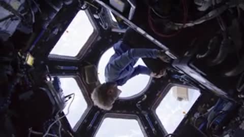 Looking down through a window at Earth from inside the station