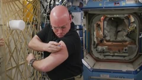 An astronaut applying a medical patch on their arm