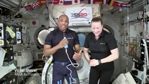 Astronauts in ISS module talking to camera.