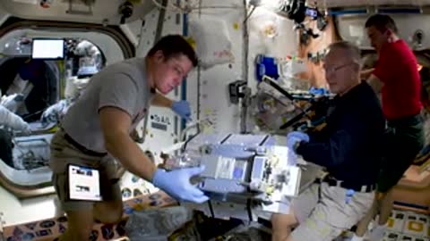 Astronauts working on equipment inside ISS module.