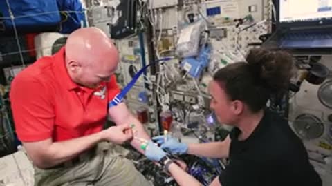 An astronaut assisting another with a medical procedure