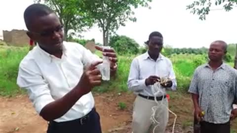 Man holding small glass vial outdoors.