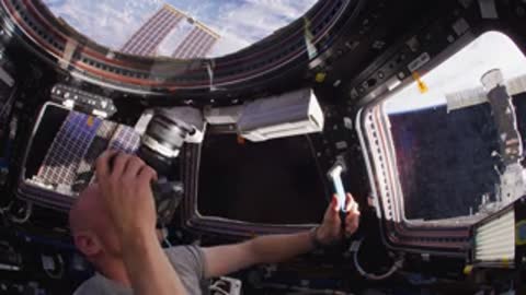 Astronaut taking photograph through window.