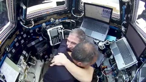 Astronauts hugging inside ISS module.