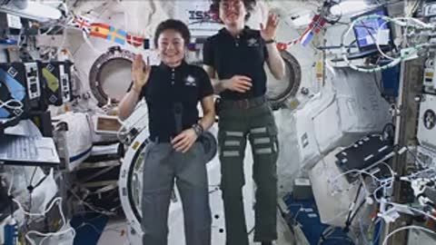 Astronauts floating and waving in station.