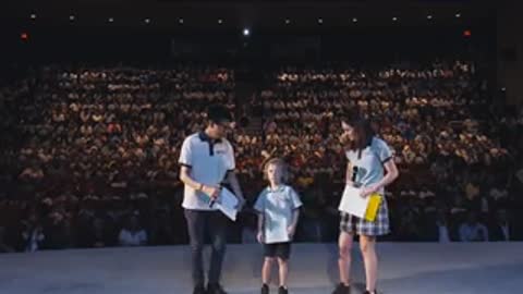 People stand on a stage before an audience in an auditorium.
