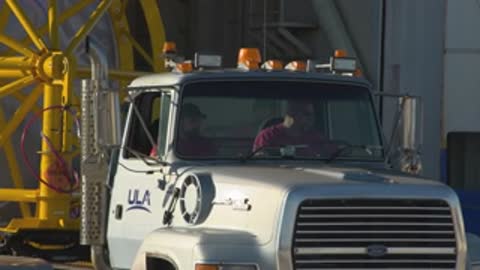 Close-up tracking shot of the semi-truck cab moving with workers visible inside.