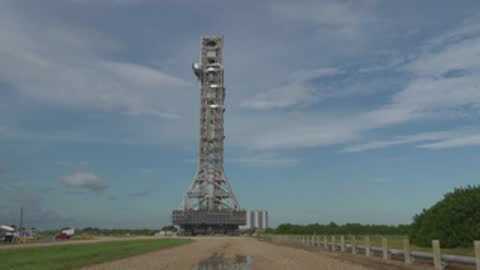 Wide shot of mobile launcher moving down the crawlerway road.