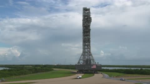 Wide shot of the mobile launcher on crawlerway moving slowly.