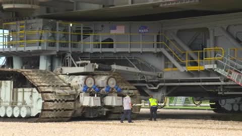 Close-up of the crawler transporter tracks with workers standing nearby.