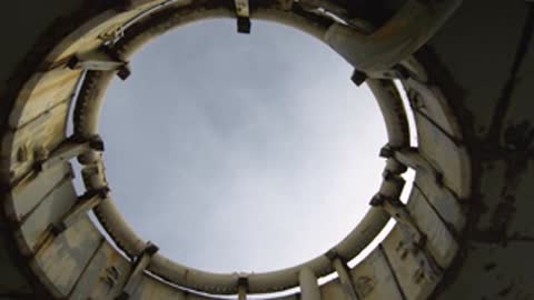 Direct upward view through the circular roof opening against a pale sky