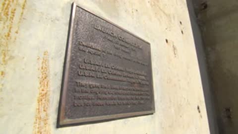 Close-up of a bronze plaque mounted on a concrete wall.